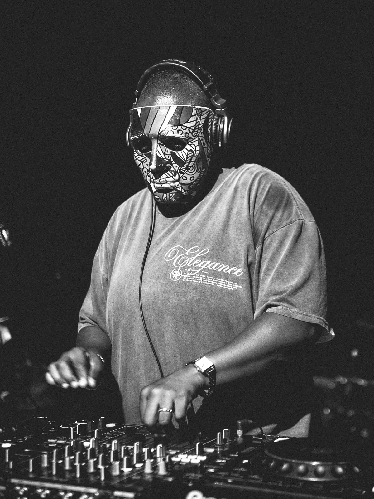 A DJ in a mask at the decks, black and white