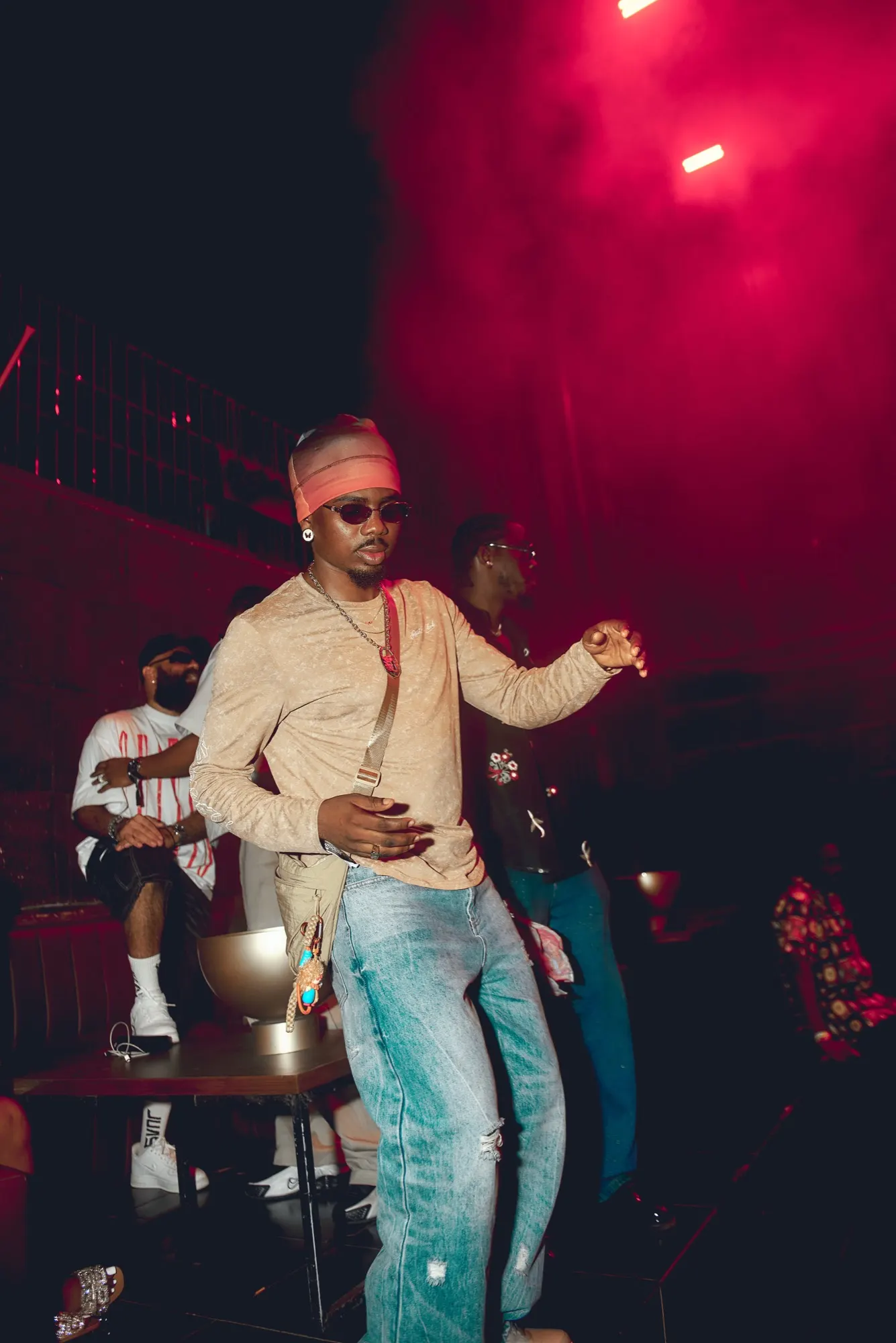 A dancer in a headband under red light at ENZO, Accra